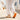 Grove barefoot sneaker in cream with orange sole, worn walking a whitewashed village street