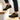 Trailblazer barefoot hiking shoe in black with yellow, worn as a pair on wooden steps, side view