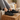 Cascade barefoot sneaker in black with grey, worn with feet resting on a wooden stump indoors