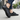 Cascade barefoot sneaker in black with grey, worn on a city sidewalk, side view
