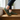 Anchor barefoot sneaker in olive green worn on wooden stairs, three quarter view