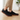 Stride barefoot sneaker in black knit with gum sole, side view worn on a wood floor