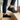 Meridian cushioned barefoot sneaker in black worn on wooden stairs, three quarter view