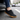 Ease barefoot slip on shoe in black, close up worn stepping out of a car onto asphalt