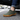 Ease barefoot slip on shoe in olive green, close up worn beside a car on asphalt