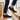 Loafers barefoot slip on shoe in black worn on wooden stairs, three quarter view