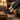 Pulse barefoot sneaker in black with gum sole, worn with feet up on a leather bench indoors, side view
