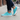 Wave barefoot sneaker in teal, pair worn on a city sidewalk, side view