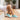 Wave barefoot sneaker in teal, worn crossing legs on a sunlit patio step