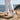Terra barefoot trainer in white, worn on a coastal cliff path, rear view showing the sole tread