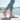 Cascade barefoot sneaker in pink with teal, worn on a sunny harbor waterfront, side view