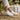 Flow barefoot slip on sneaker in white, worn seated at a sunny garden brunch table, side view