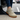 Summit barefoot hiking shoe in khaki taupe with orange sole, worn stepping out of a car