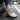 Trailblazer barefoot hiking shoe in light grey with orange, single shoe worn stepping out of a car, side view