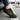 Trailblazer barefoot hiking shoe in black with yellow trim, single shoe worn stepping out of a car, side view