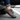 Trailblazer barefoot hiking shoe in dark grey with orange, single shoe worn on a road, side view