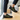 Trailblazer barefoot hiking shoe in black with lime green, worn as a pair on a wooden step indoors, side view