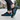 Cascade barefoot sneaker for men in black with teal blue, worn on a city sidewalk, side view