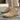 Haven barefoot lace up shoe in tan worn on a wooden deck, front view