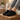 Flow barefoot slip on sneaker in black, worn resting on a wooden block indoors, side view of the quilted upper