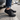 Sage barefoot sneaker in all black worn stepping out of a car, front view