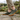 Ease barefoot slip on shoe in olive green, worn side view on stone paving in a garden
