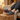 Wave barefoot sneaker in grey with a gum sole, resting feet on a wooden stool in a living room