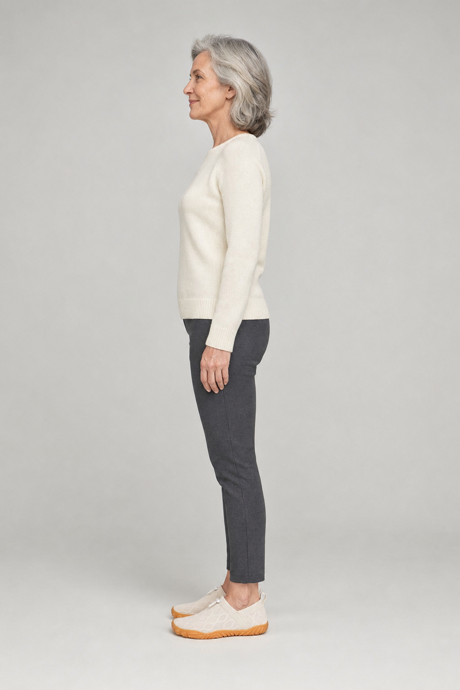 A woman standing in the Ease shoes, side view showing her hips, knees, ankles and the ball of her foot