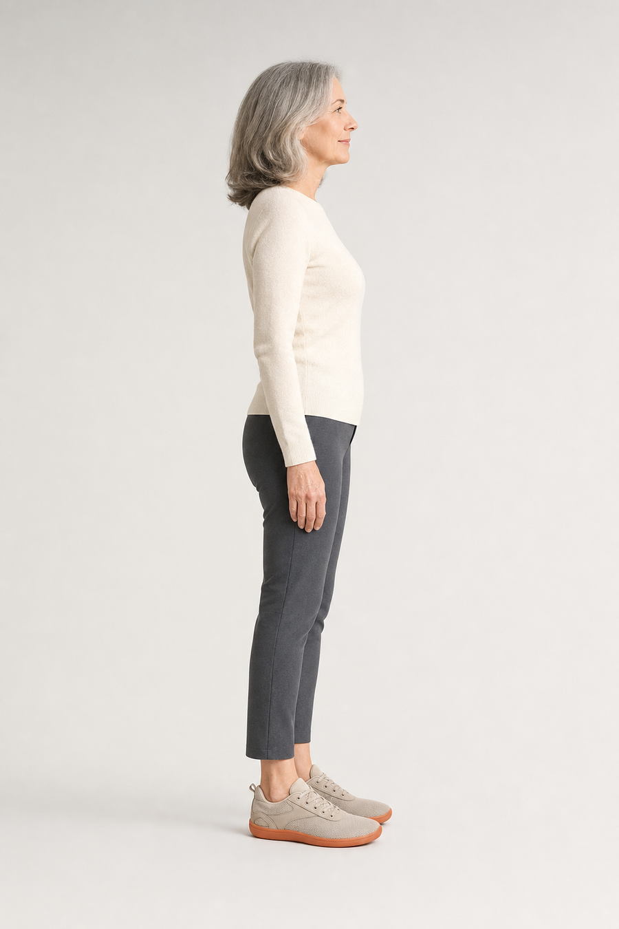 A woman standing in the Grove shoes, side view showing her hips, knees, ankles and the ball of her foot